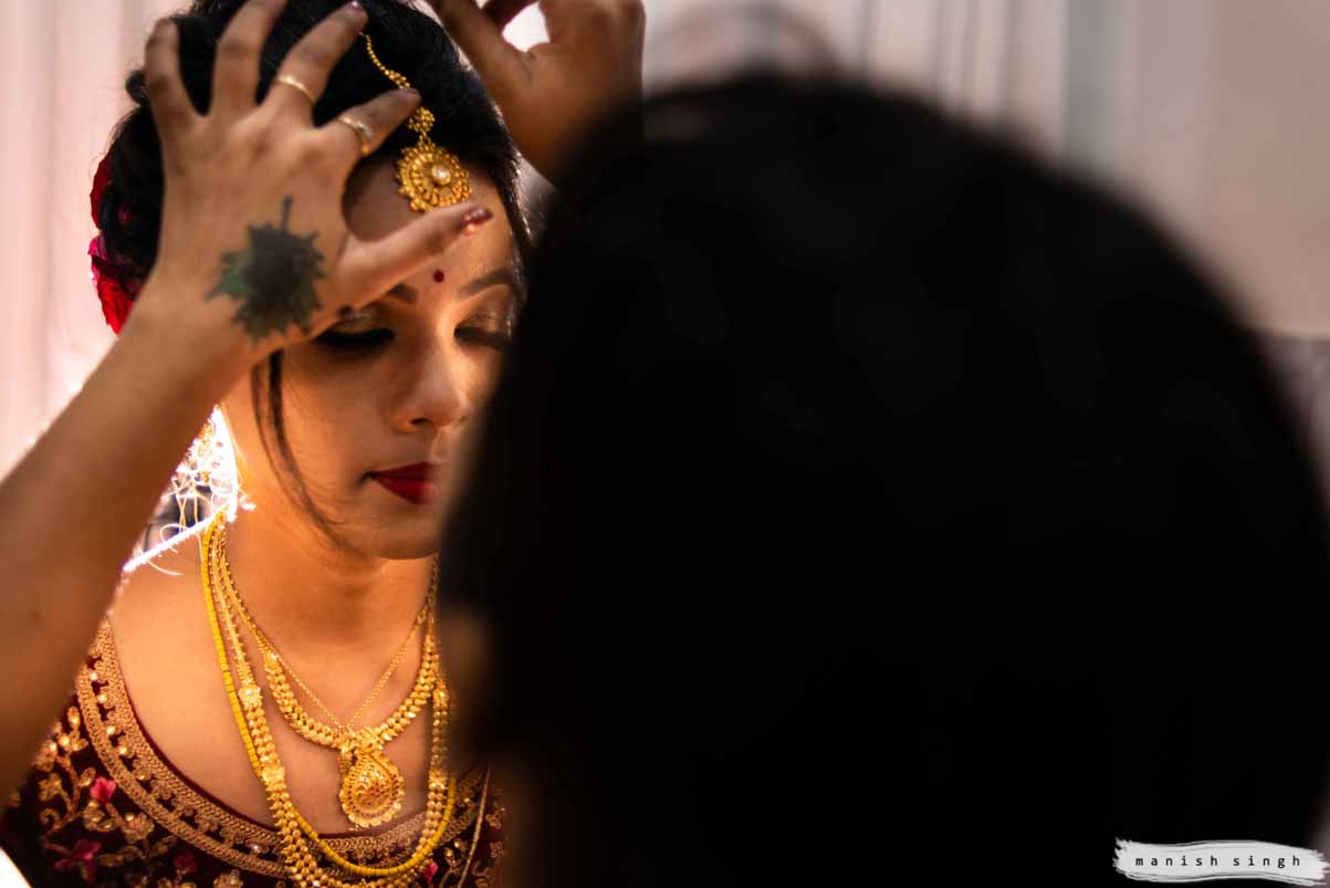 makeup artist adjusting bride's maang tika