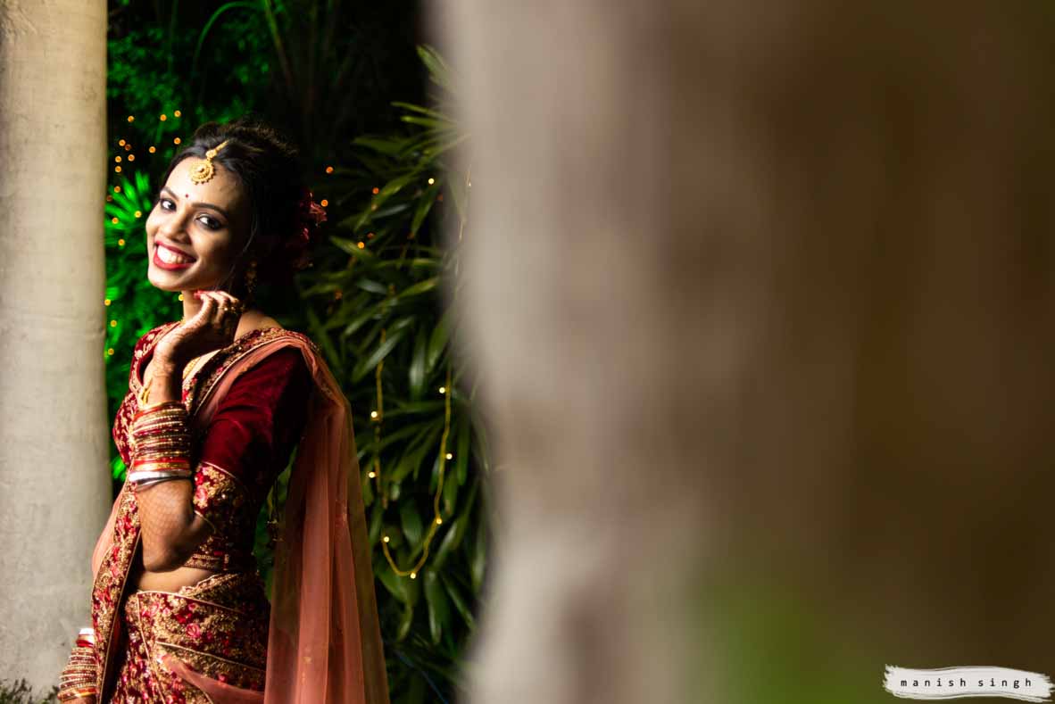 Beautiful bride in red lehenga looking at the camera and smiling