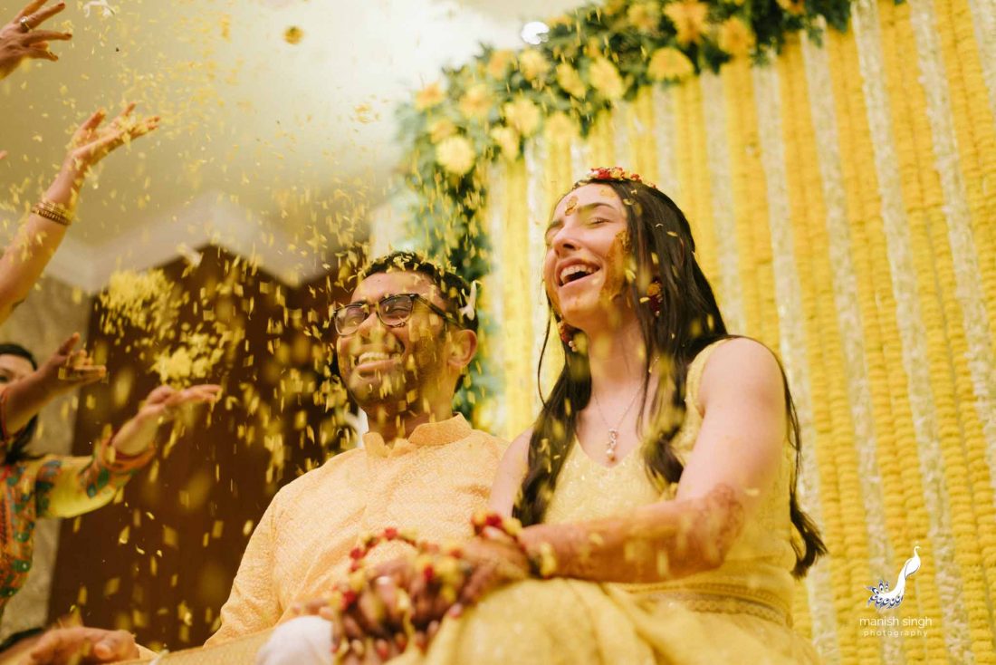 yellow flower shower on couple during haldi ceremony