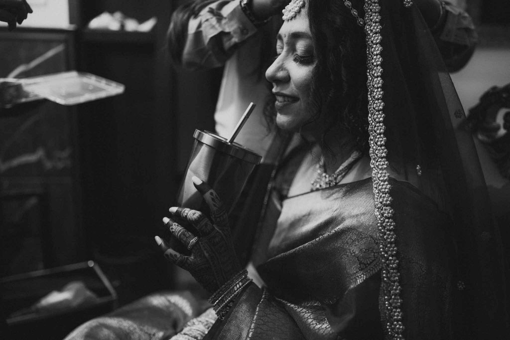 bride with sipper while getting ready for wedding