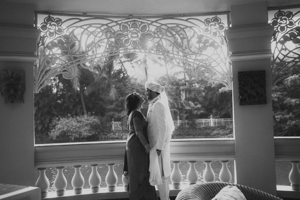 bride and groom face each other and talk in front of lake in Mayfair lagoon Bhubaneswar